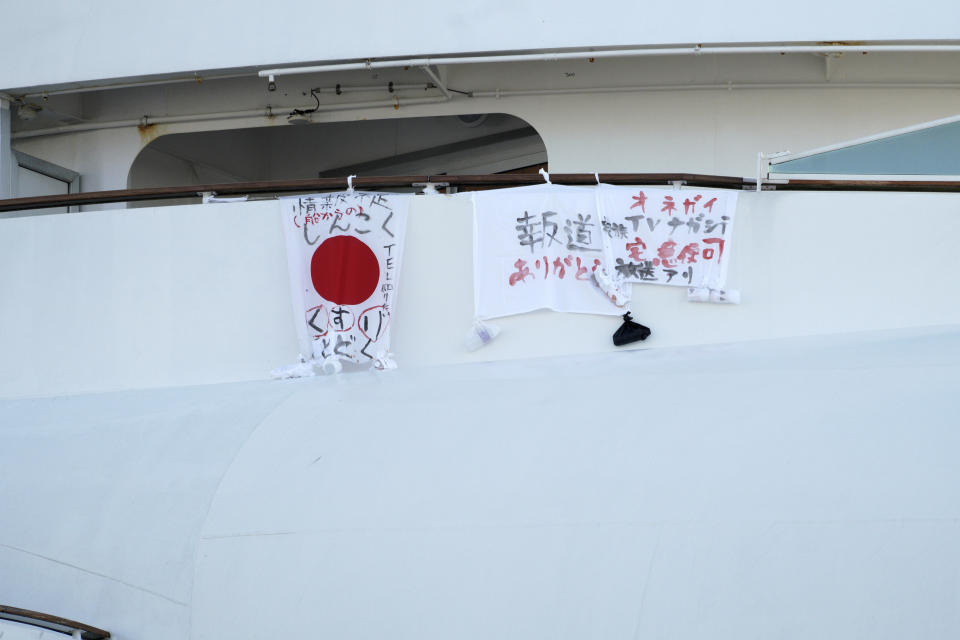 Some banners are hang by passengers of the cruise ship Diamond Princess anchored off the Yokohama Port Monday, Feb. 10, 2020. China reported a rise in new virus cases on Monday, possibly denting optimism disease control measures that have isolated major cities might be working, while Japan reported dozens of new cases aboard the quarantined cruise ship. (AP Photo/Eugene Hoshiko)