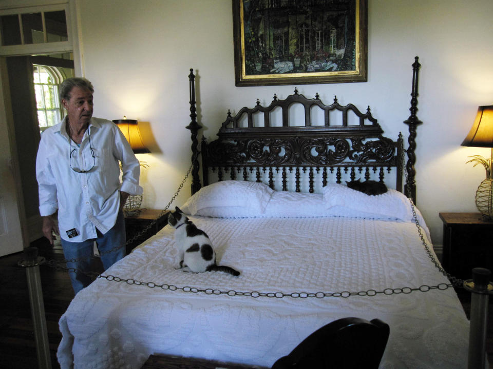 This February 2013 photo shows tour guide Bob Smith at the Hemingway Home in Key West, Fla., with one of the home’s cats, named Fats Waller. The home belonged to the late author Ernest Hemingway, who had a six-toed cat, and many of the 40 to 50 cats who reside there today have the polydactyl gene for an extra toe. The cats, named for celebrities, have free run of the house. (AP Photo/Beth J. Harpaz)
