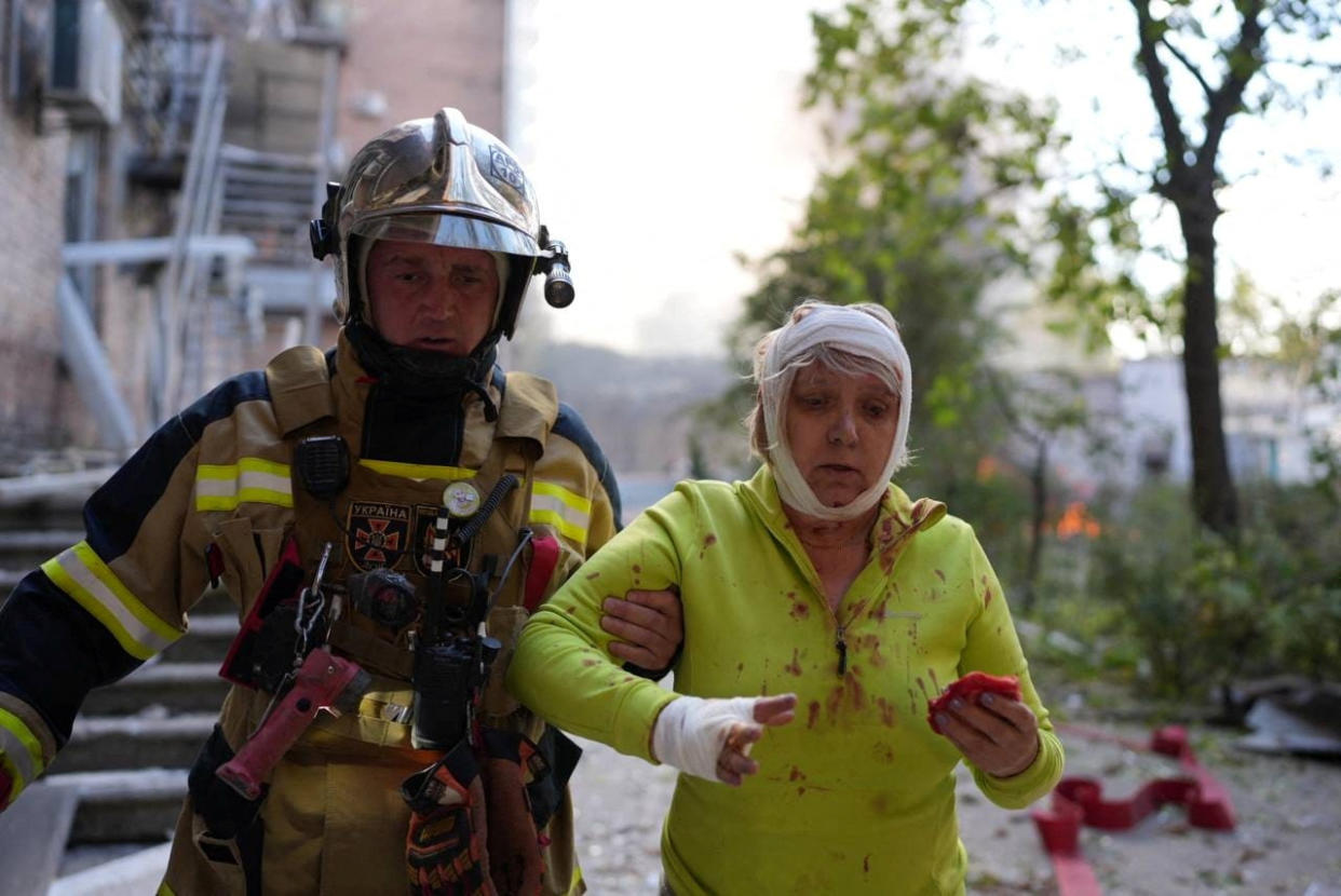 A rescuer helps an injured woman at a site of a building damaged by a Russian missile strike, amid Russia's attack on Ukraine, in Kyiv, Ukraine October 10,