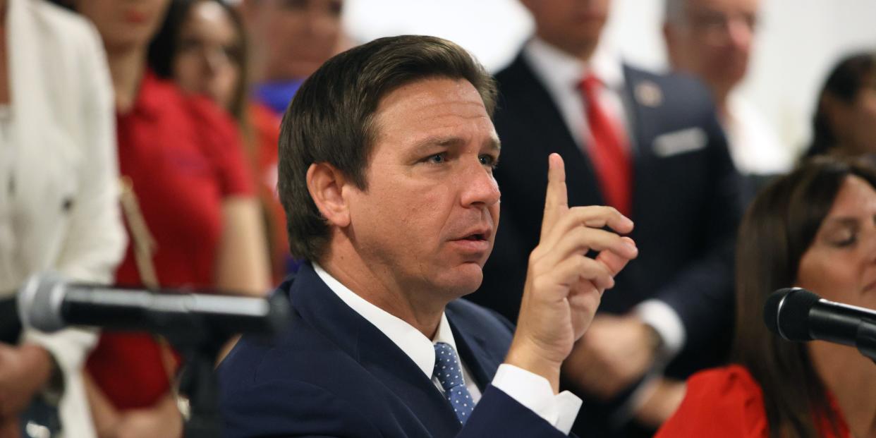 Florida Gov. Ron DeSantis raises his hand.