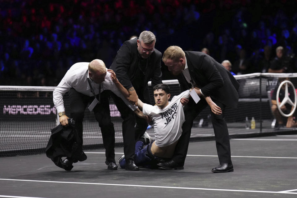 Stewards remove a protester after he set a fire on the court on day one of the Laver Cup at the O2 Arena in London, Friday Sept. 23, 2022. (John Walton/PA via AP)