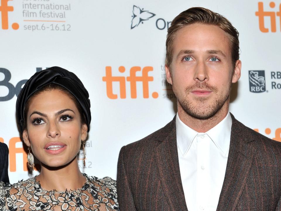 Eva Mendes in a black headband next to Ryan Gosling in a white shirt and brown suit jacket