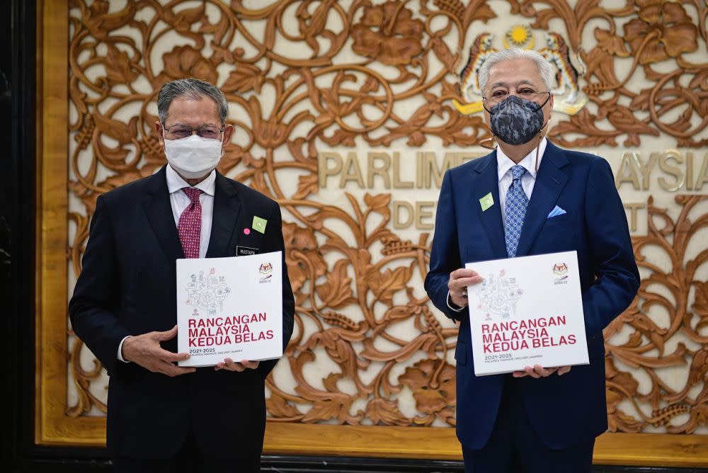 Prime Minister Datuk Seri Ismail Sabri Yaakob (right) poses with a copy of the 12th Malaysia Plan alongside Datuk Seri Mustapa Mohamed at Dewan Rakyat, Kuala Lumpur September 27, 2021. — Bernama pic