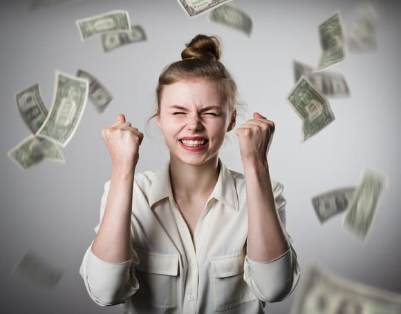 Smiling woman with money raining down on her