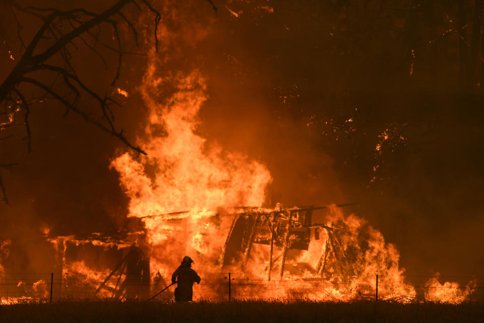 Firefighter battling blaze as thunderstorms threaten to start new fires.