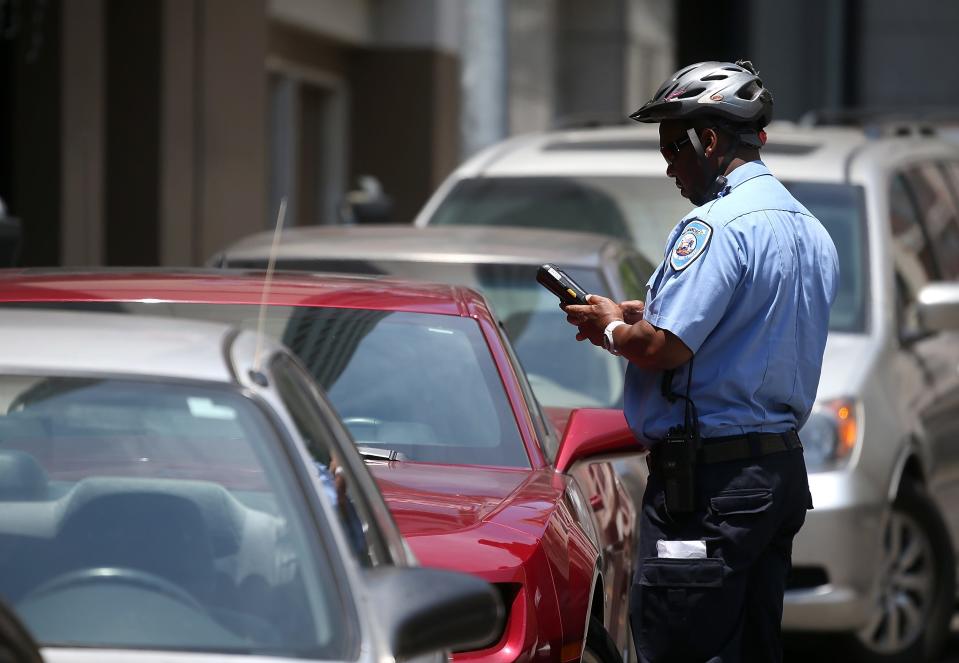 A San Francisco Municipal Transportation Agency parking control officer writes a parking ticket for an illegally parked car on July 3, 2013 in San Francisco, California.