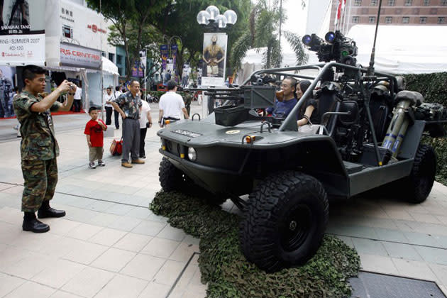 A Singapore military personnel takes photograph of a couple sitting in a light strike vehicle displayed along Orchard Road walkway which is part part of a show to commemorate 40 years of National Service in Singapore, 12 April 2007. (AFP photo)