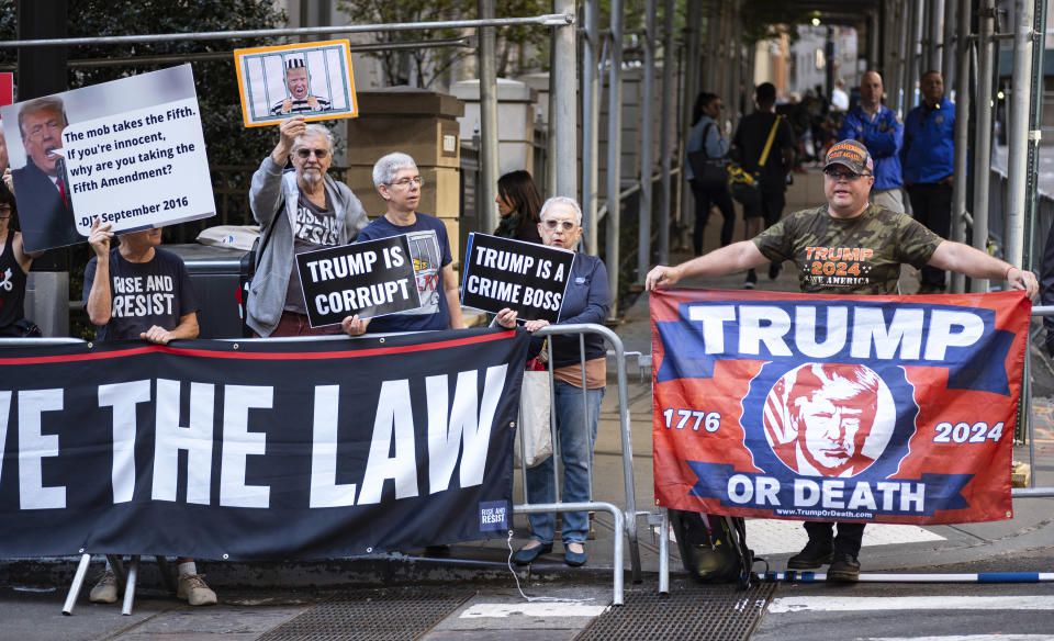 Protesters gather before former President Donald Trump arrives in a motorcade for a deposition in New York Thursday, April 13, 2023. (AP Photo/Craig Ruttle)