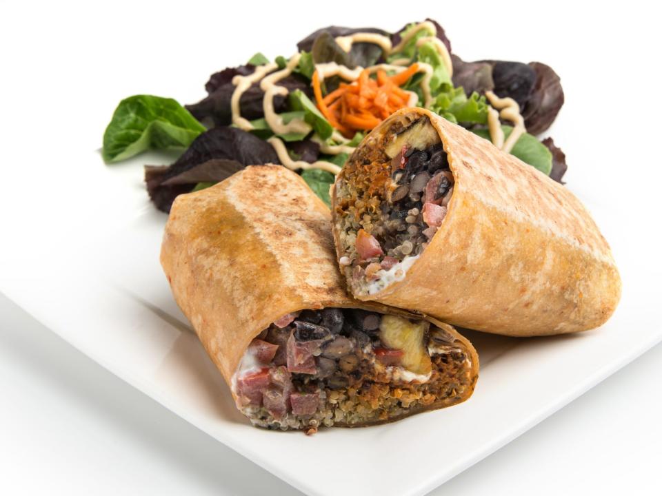 a black bean and veggie wrap on a whole wheat tortilla with a side salad