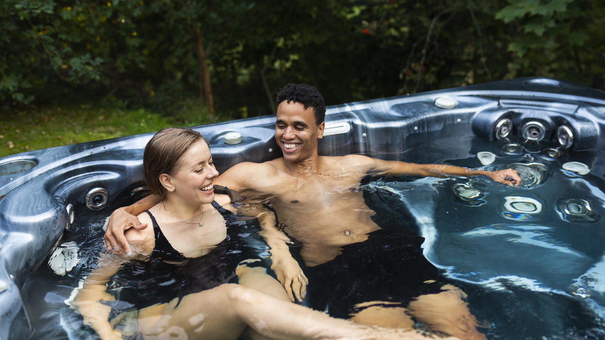  Man and woman sat next to each other in hot tub. 