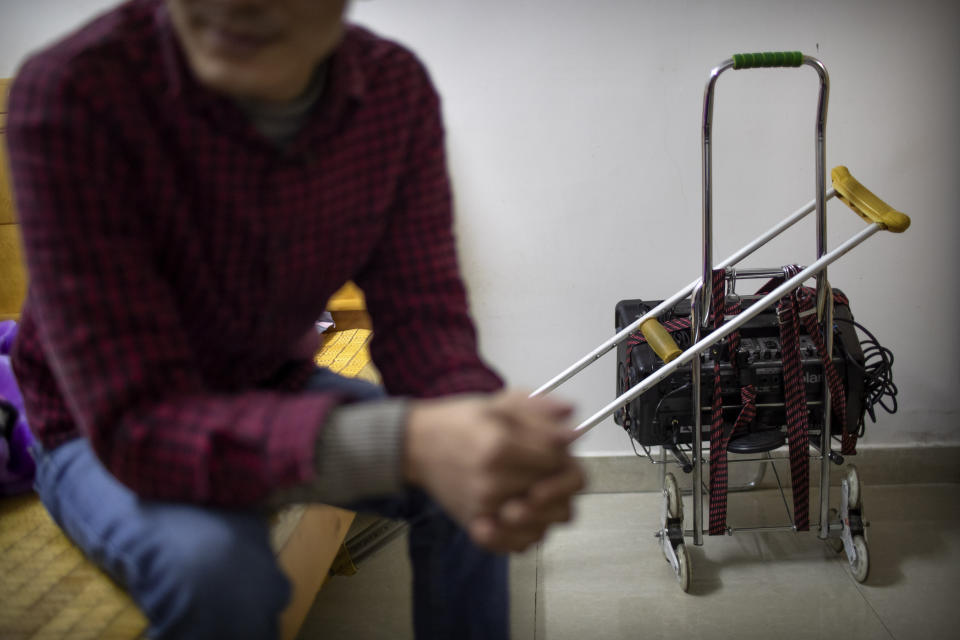 In this Dec. 5, 2019 photo, Wu Yi, who has struggled with Oxycontin abuse, sits in his rented room near his crutch and the portable amplifier he uses to sing songs for money in Shenzhen, southern China's Guangdong Province. Officially, pain pill abuse is an American problem, not a Chinese one. But people in China have fallen into opioid abuse the same way many Americans did, through a doctor's prescription. And despite China's strict regulations, online trafficking networks, which facilitated the spread of opioids in the U.S., also exist in China. (AP Photo/Mark Schiefelbein)