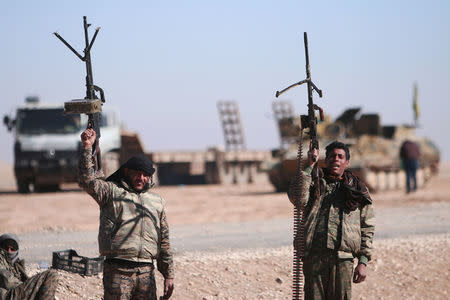 Syrian Democratic Forces fighters hold up their weapons in the north of Raqqa city, Syria. REUTERS/Rodi Said