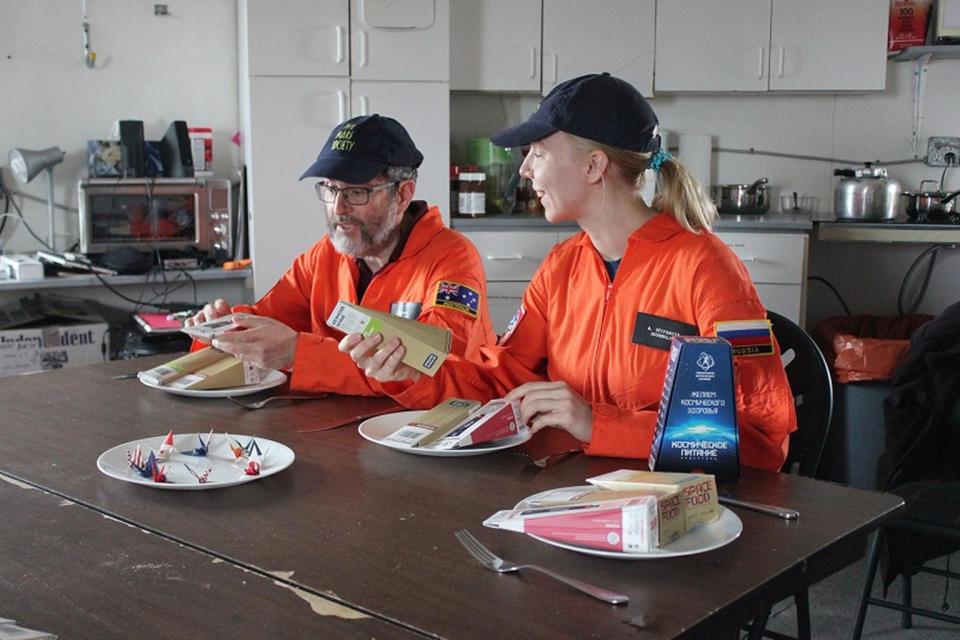Mars 160 crewmembers Jon Clarke and Anastasiya Stepanova get ready to dig into some Russian space food for dinner. <cite>The Mars Society</cite>