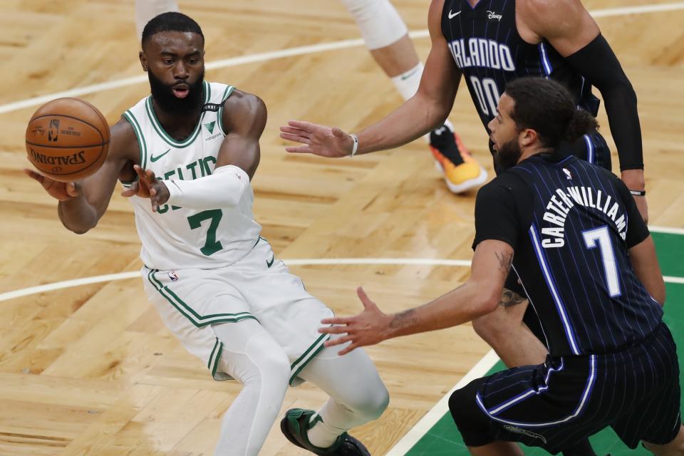Boston Celtics' Jaylen Brown, left, passes off against Orlando Magic's Michael Carter-Williams during the first half on an NBA basketball game, Sunday, March 21, 2021, in Boston. (AP Photo/Michael Dwyer)