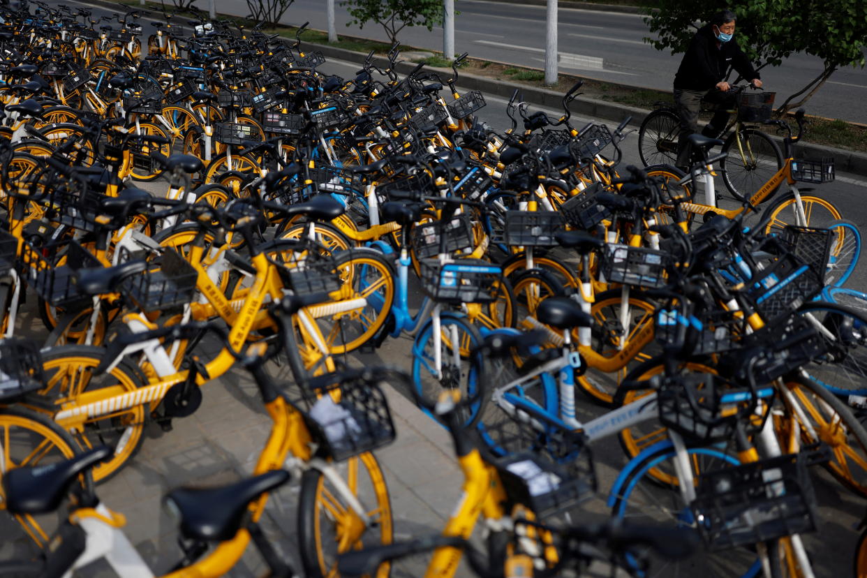 A cyclist rides past bicycles of bike-sharing services parked on the street near a subway station in Beijing, China. (Reuters file photo)