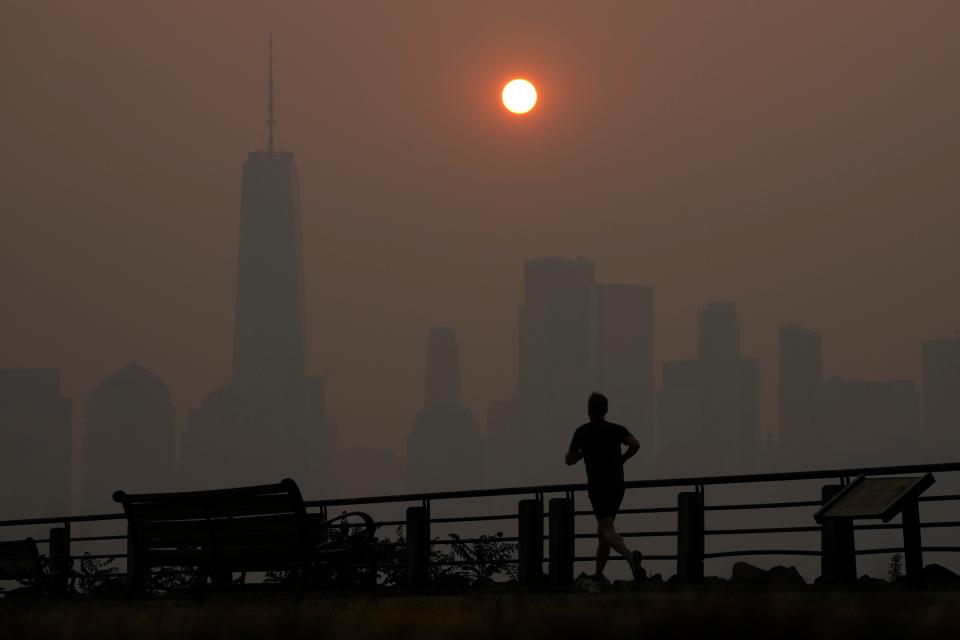 A man runs in front of the sun rising over the lower Manhattan skyline in Jersey City, N.J., on June 8. Intense Canadian wildfires are blanketing the northeastern U.S. in a dystopian haze, turning the air acrid, the sky yellowish gray, and prompting warnings for vulnerable populations to stay inside.