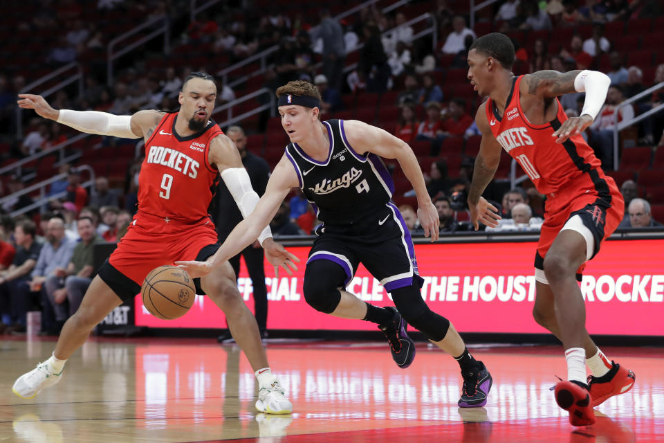 Sacramento Kings guard Kevin Huerter (9) drives between Houston Rockets forwards Dillon Brooks (9) and Jabari Smith Jr. (10) during the first half of an NBA basketball game Monday, Nov. 6, 2023, in Houston. (AP Photo/Michael Wyke)