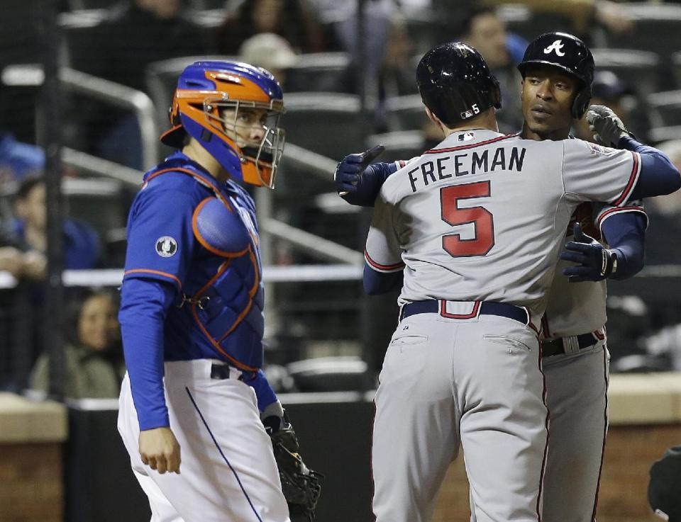 New York Mets catcher Travis d'Arnaud, left, looks away as Atlanta Braves' Freddie Freeman (5) hugs B.J. Upton during the eighth inning of a baseball game on Friday, April 18, 2014, in New York. (AP Photo/Frank Franklin II)