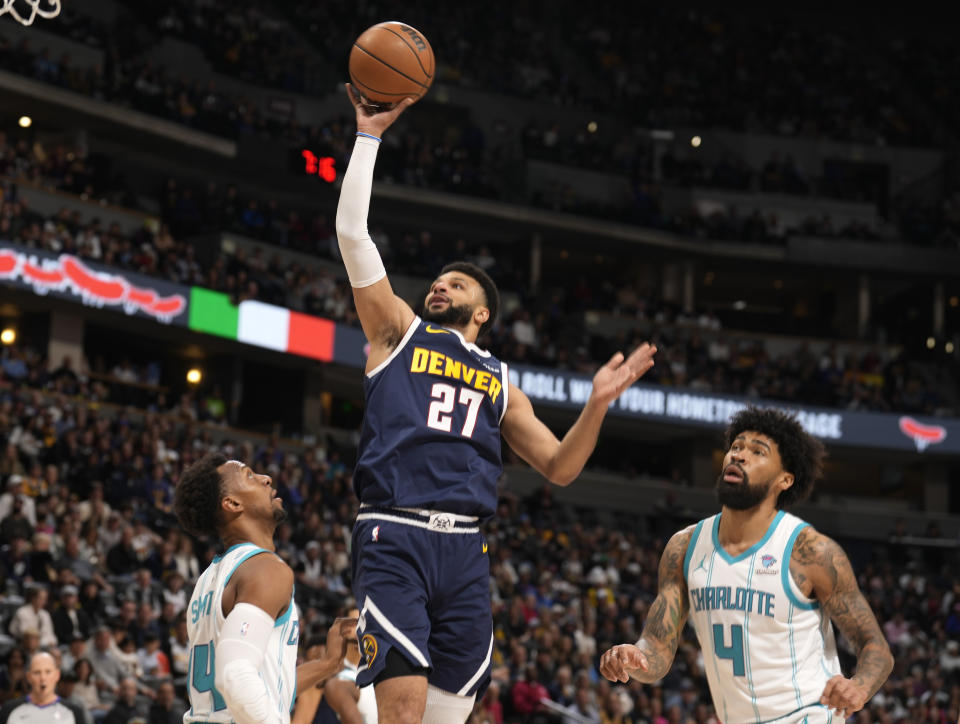 Denver Nuggets guard Jamal Murray, center, drives to the rim between Charlotte Hornets guard Ish Smith, left, and center Nick Richards in the first half of an NBA basketball game, Monday, Jan. 1, 2024, in Denver. (AP Photo/David Zalubowski)