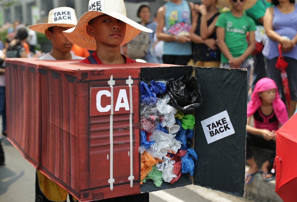 Filipino environmental activists wear a mock container vans filled with garbage to symbolize the 50 containers of waste that were shipped from Canada to the Philippines two years ago, as they hold a protest outside the Canadian embassy at the financial district of Makati, south of Manila, Philippines on Thursday, May 7, 2015. The group held the protest to assert that the country is not a waste dumping and burning zone and to call on Philippine President Benigno Aquino III to talk about the said "illegal" waste issue when he meets Canadian Prime Minister Stephen Harper during his state visit on May 7.(AP Photo/Aaron Favila)