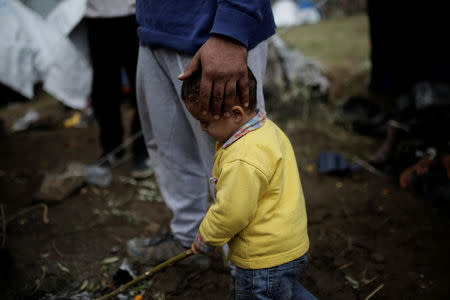 Syrian refugee Bashar Wakaa holds the head of his son at a makeshift camp for refugees and migrants next to the Moria camp on the island of Lesbos, Greece, November 30, 2017. REUTERS/Alkis Konstantinidis REUTERS/Alkis Konstantinidis