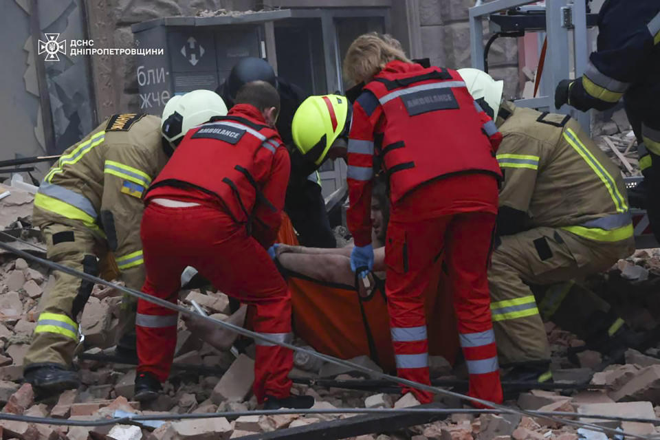 In this photo provided by the Ukrainian Emergency Service, rescuers and ambulance workers carry a person on the scene of a Russian attack in Dnipro, Ukraine, Friday, April 19, 2024. (Ukrainian Emergency Service via AP Photo)