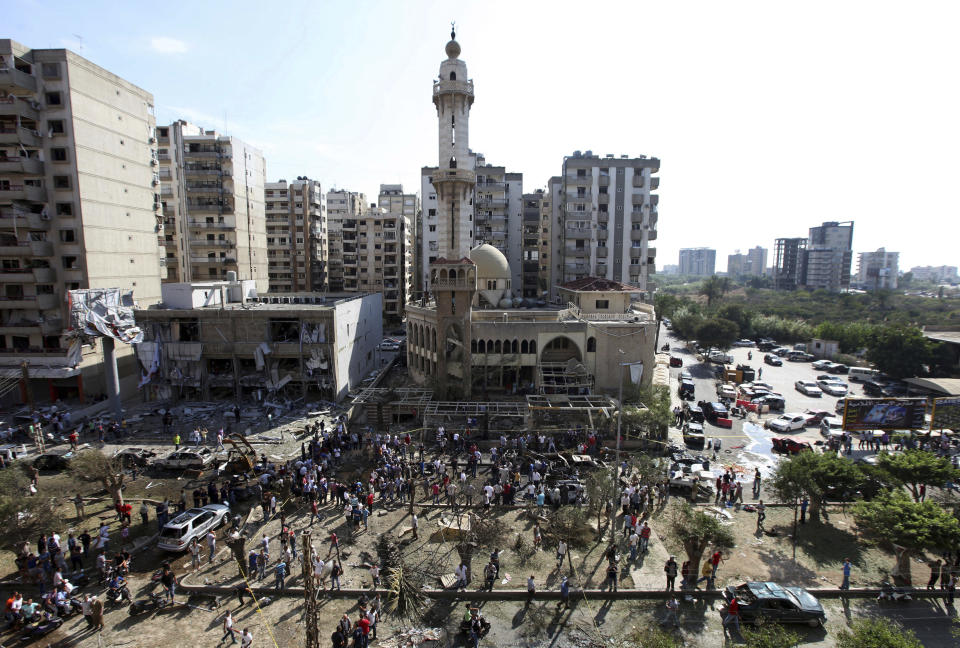 FILE - In this Friday, Aug. 23, 2013 file photo, people gather outside the al-Salam Mosque amid charred cars and wide damage at the site of a car bombing, which killed dozens, in the northern city of Tripoli, Lebanon. A Lebanese court has sentenced Friday, Nov. 1, 2019 a man to death in a 2013 twin car bombs in the northern city of Tripoli that killed 47 people. (AP Photo/Bilal Hussein, File)