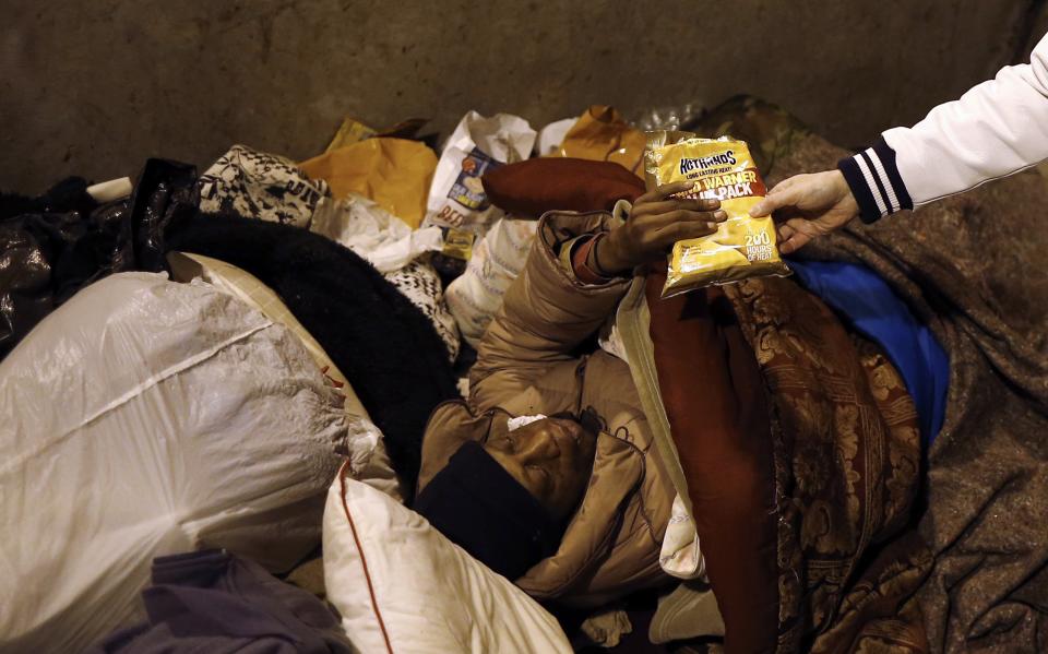 Doctor Patrick Angelo hands out hand warmers to a homeless person under the overpasses on Lower Wacker Drive in Chicago, Illinois, January 7, 2014. Angelo visits the homeless several times a week to hand out food, clothing and blankets to those living on the streets with funding coming from his oral surgery practice and profits from his healthcare company. Angelo is in his 13th year doing charity work. Picture taken January 7, 2014. REUTERS/Jim Young (UNITED STATES - Tags: SOCIETY POVERTY)