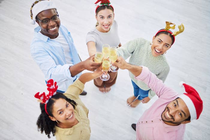 People wearing Christmas garb and clinking glasses