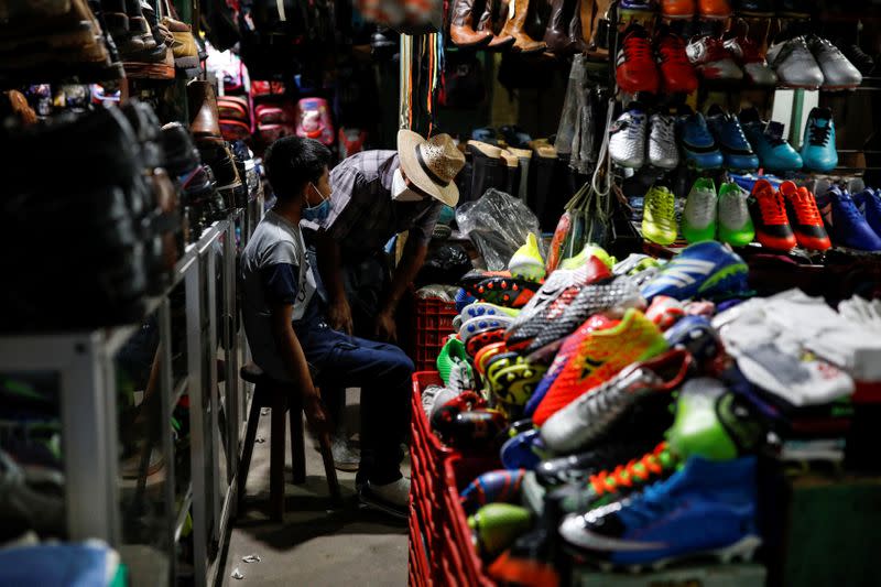 Juan talks to his disabled 12-year-old son Gustavo, who was expelled by U.S. authorities to Guatemala under an emergency health order, whilst buying a pair of plastic rain boots at a market after being reunited in Peten