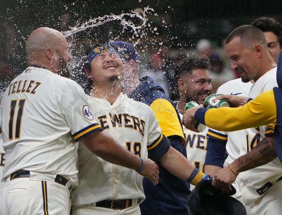 Keston Hiura is swarmed by Brewers teammates after hitting a two-run home run during the eleventh inning Wednesday afternoon to beat the Braves.