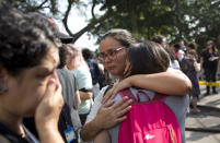 National Museum personnel embrace outside the burned National Museum in Rio de Janeiro, Brazil, Monday, Sept. 3, 2018. A huge fire engulfed Brazil's 200-year-old museum which houses artifacts from Egypt, Greco-Roman art and some of the first fossils found in Brazil. (AP Photo/Silvia Izquierdo)