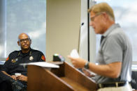 Waterloo Police Chief Joel Fitzgerald, left, listens to Cedar Valley Backs the Blue chairman Lynn Moller speak during a City Council meeting, Tuesday, Sept. 7, 2021, in Waterloo, Iowa. Fitzgerald, the first Black police chief in Waterloo, is facing intense opposition from some current and former officers as he works with city leaders to reform the department, including the removal of its longtime insignia that resembles a Ku Klux Klan dragon. (AP Photo/Charlie Neibergall)