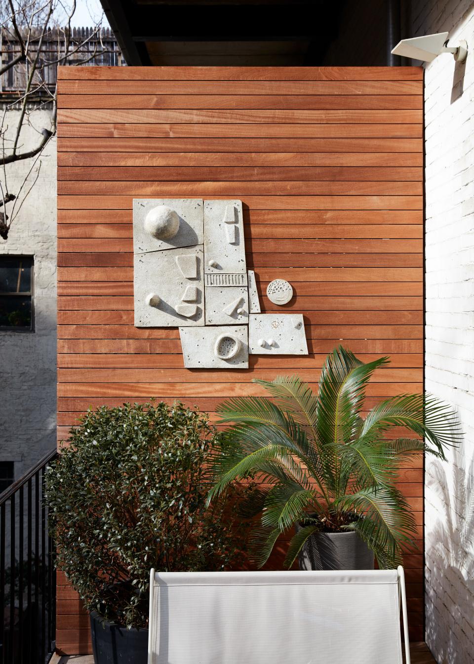 Of his south-facing sun-drenched balcony, Otero says, “It's pretty much my favorite place in my apartment! It really is an oasis—very calm.” He designed the deck and side wall panels in mahogany. One of his pieces hangs on a side panel.