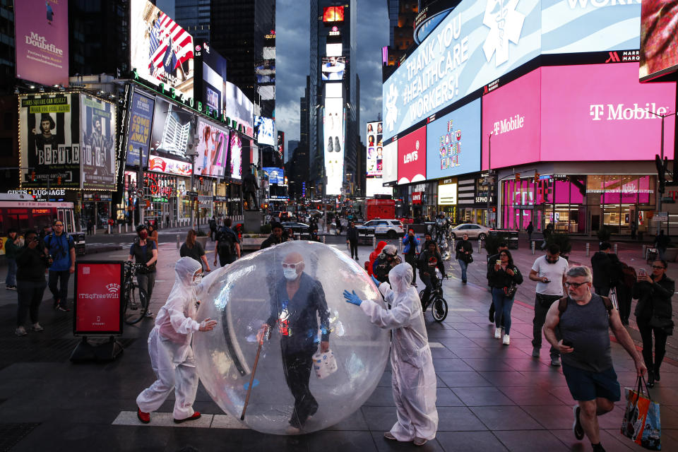 Artists perform under a billboard displaying thanks to healthcare workers due to COVID-19 concerns in a sparsely populated Times Square, Friday, March 20, 2020, in New York. New York Gov. Andrew Cuomo is ordering all workers in non-essential businesses to stay home and banning gatherings statewide. "Only essential businesses can have workers commuting to the job or on the job," Cuomo said of an executive order he will sign Friday. Nonessential gatherings of individuals of any size or for any reason are canceled or postponed. (AP Photo/John Minchillo)