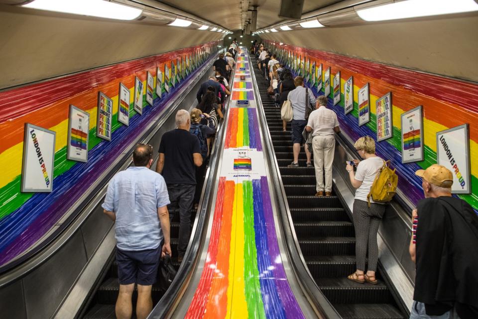 <p>People ride a tube escalator decorated with the Pride flag colours. (Carl Court/Getty Images) </p>