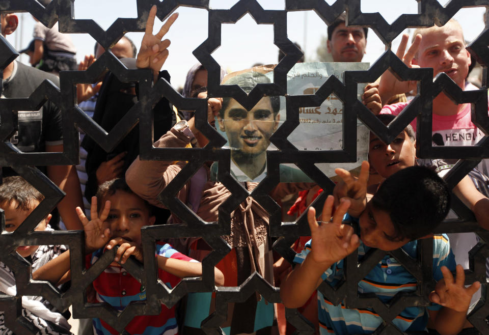 Palestinians wait for the Arab Idol winner Palestinian Mohammed Assaf, unseen, at the entrance of Rafah crossing point on the border between Egypt and southern Gaza Strip, Tuesday, June 25, 2013. Huge crowds of Gazans gave a gleeful welcome Tuesday to the first Palestinian winner of the Arab Idol talent contest, thronging the territory's border crossing with Egypt and the singer's home in hopes of embracing him, but internal politics surfaced quickly. Assaf’s victory in the popular contest Saturday sparked huge celebrations in the West Bank and Gaza, giving Palestinians a sense of pride. (AP Photo/ Hatem Moussa)