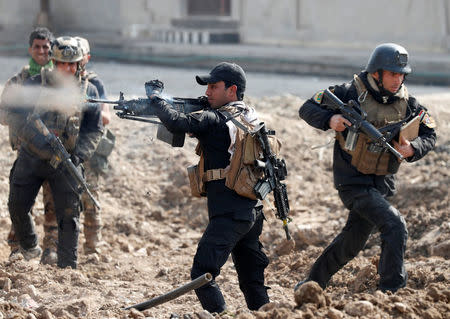 An Iraqi special forces soldier fires as other soldiers runs across a street during a battle in Mosul, Iraq March 1, 2017. REUTERS/Goran Tomasevic