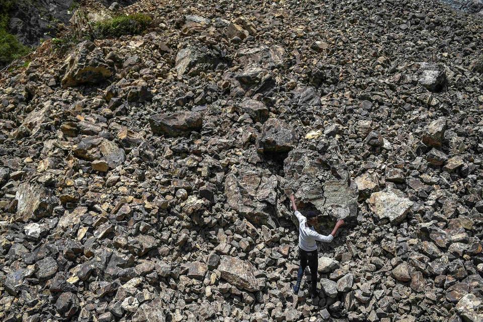 A man walks over rubble that covered a road during a landslide triggered by the earthquake in River Glass on Aug. 18.<span class="copyright">Matias Delacroix—AP</span>