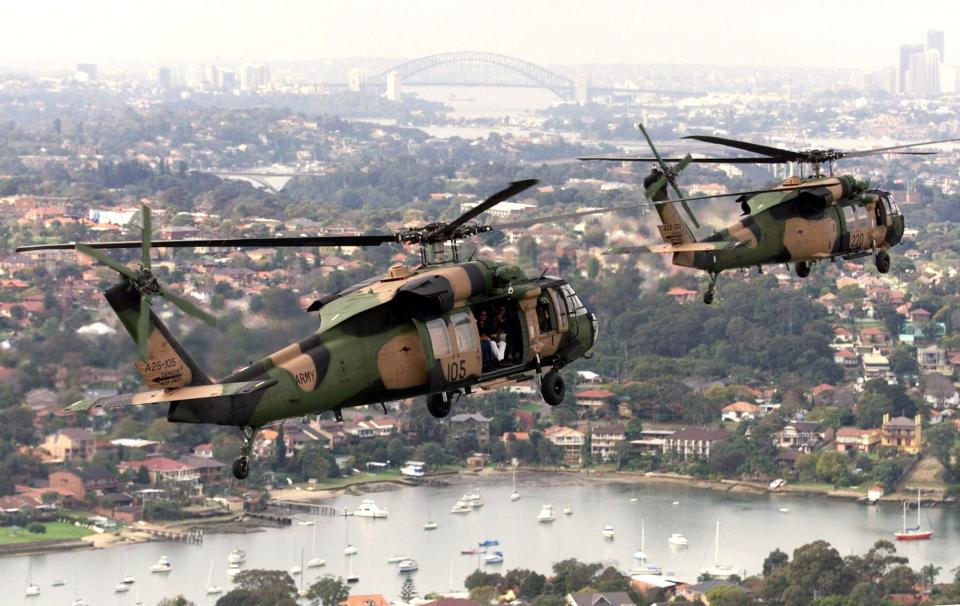 Two Australian Defence Force (ADF) S70A-9 Blackhawk helicopters fly in formation along Sydney's Parramatta River in 1999.