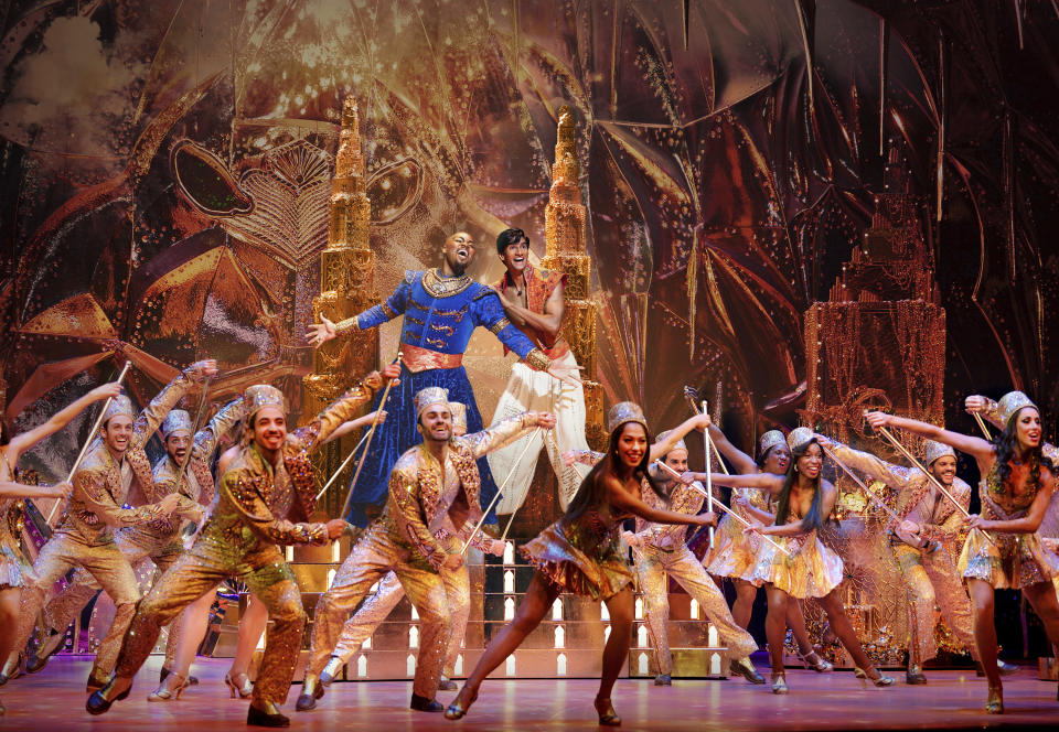 This image released by Disney Theatricals shows Michael James Scott as Genie, background left, and Michael Maliakel as Aladdin, background right, during a performance of "Aladdin on Broadway." (Matthew Murphy/Disney Theatricals via AP)