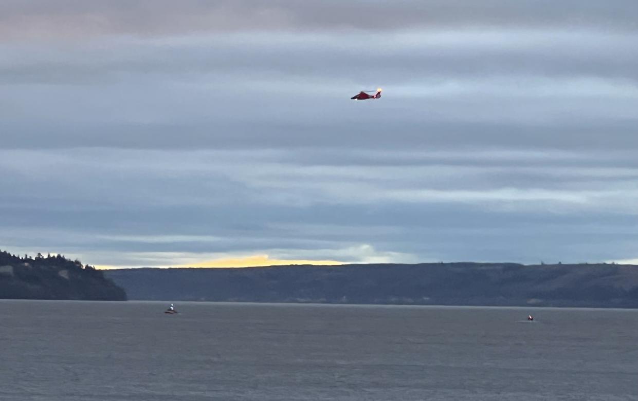 A Coast Guard helicopter searches the area where a floatplane crashed near Whidbey Island, Wash., Sunday.