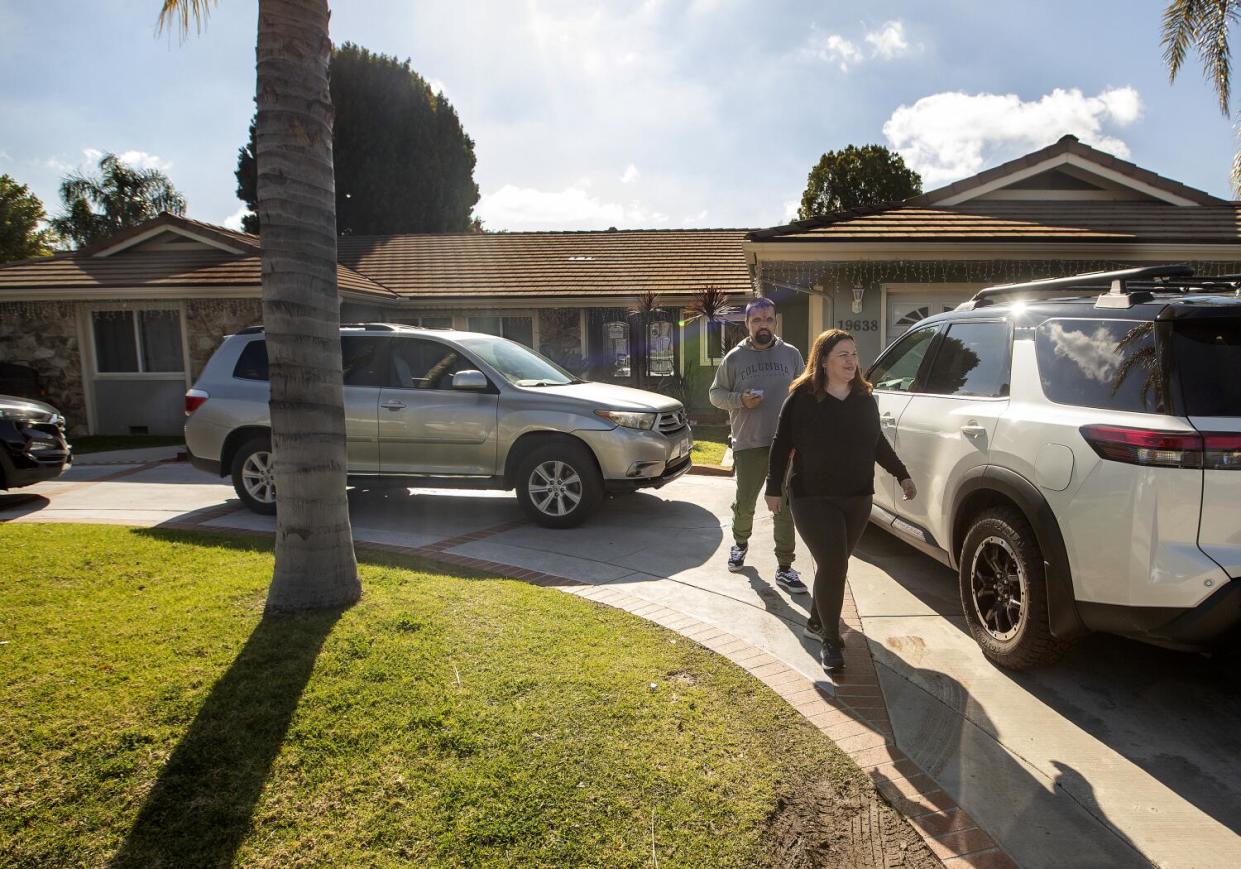 Two people walk on a sidewalk