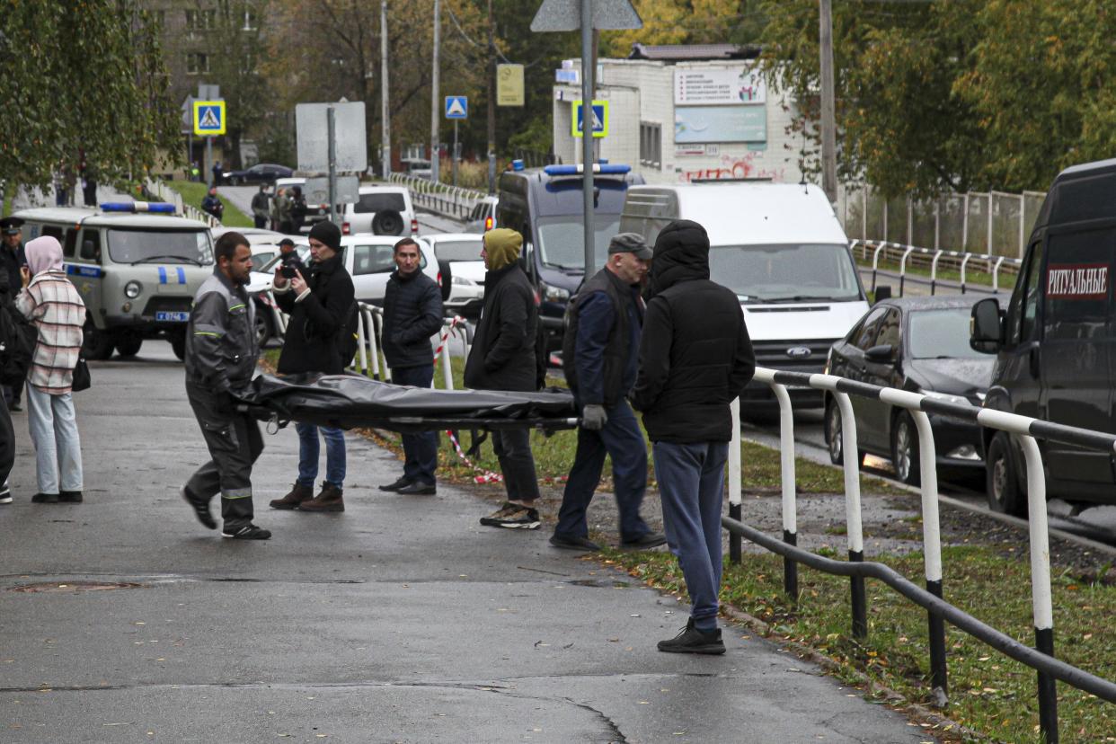 Funeral workers carry a body of victim at the scene of a shooting at school No. 88 in Izhevsk, Russia, Monday, Sept. 26, 2022. 