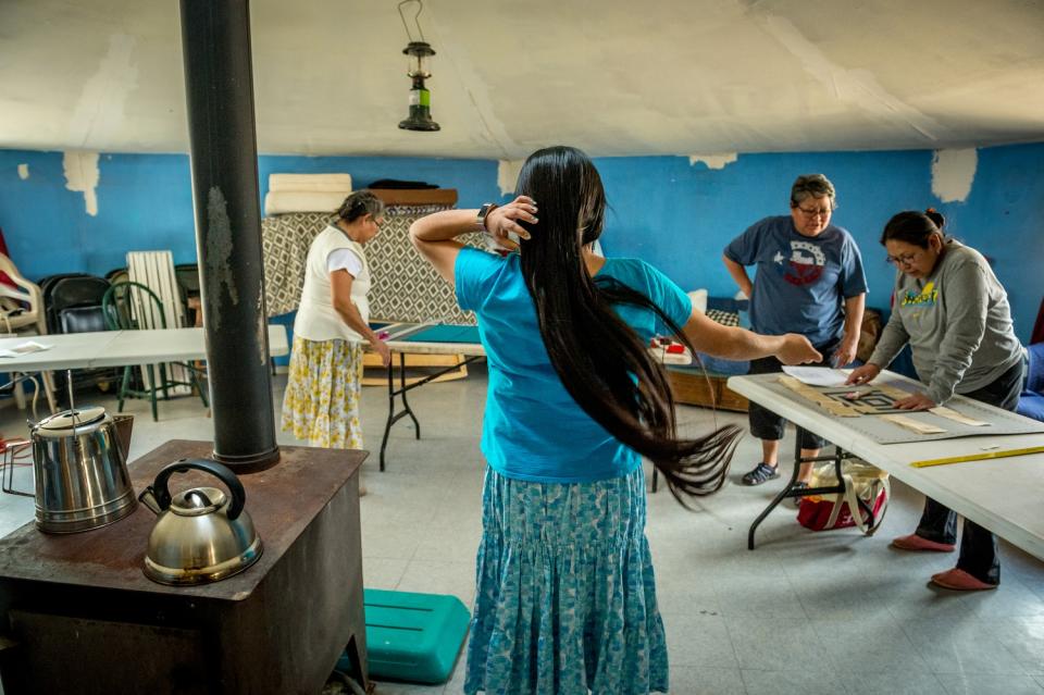 Tara Begay fixes her hair while sisters Carol Talker, Leona Begishie and Linda Talker, work on a quilt in their family hogan (traditional Navajo house) in Cameron, AZ. (Photograph by Mary F. Calvert)