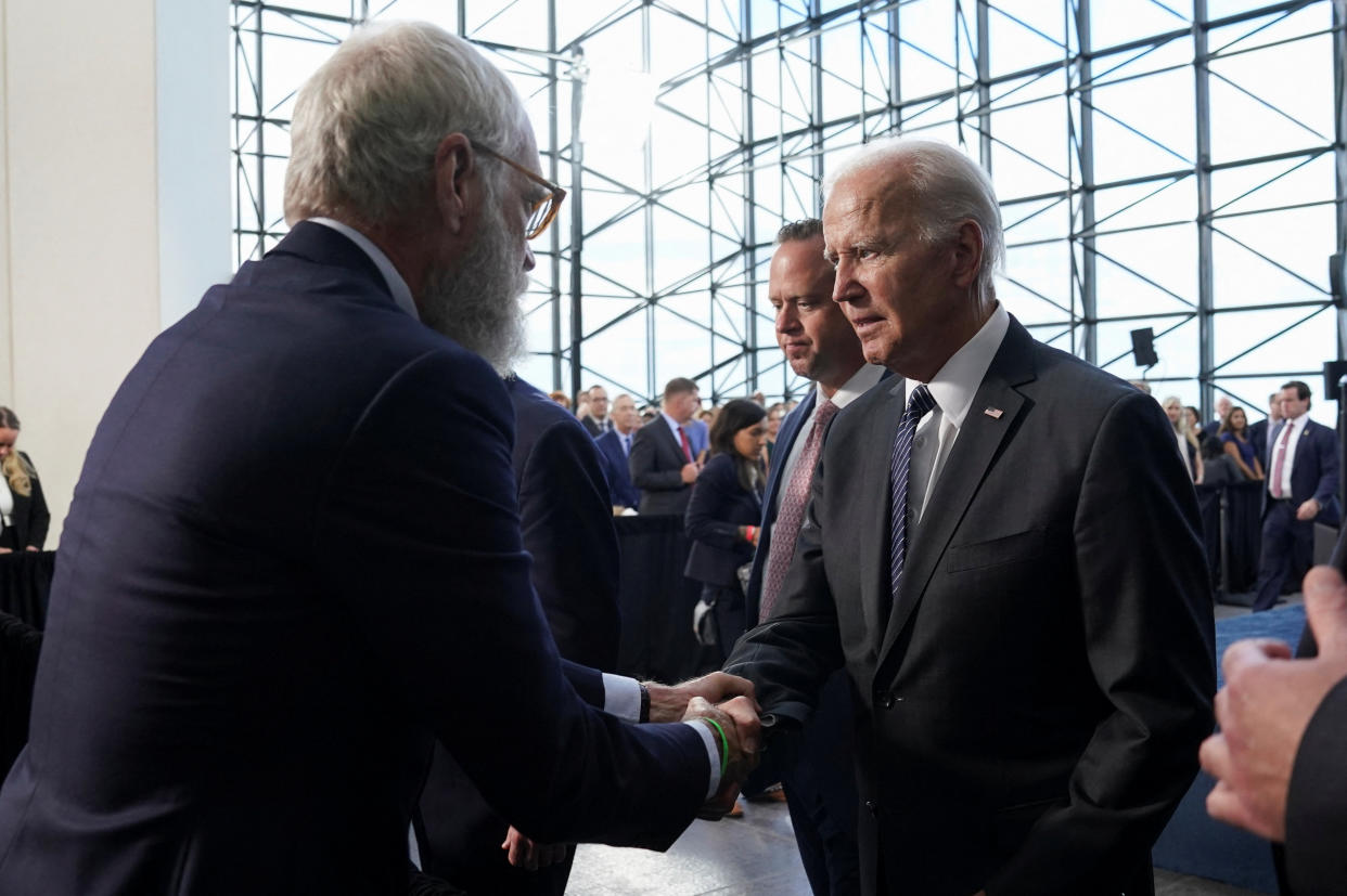 U.S. President Joe Biden shakes hands with talk show host and interviewer David Letterman after delivering a speech on his 