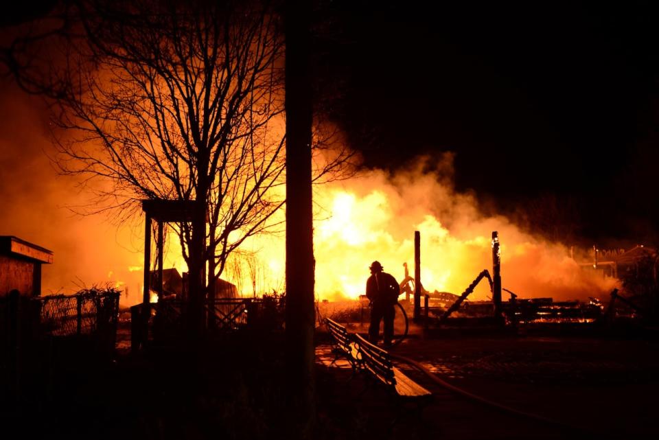 Ward's Island Association Clubhouse, and the Island Cafe it housed, was completely gutted by a fire early Sunday morning. A firefighter is pictured on scene. (Claudette Abrams/Facebook - image credit)