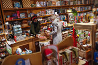 Owner of Kinkajou toy shop Sarah De Kinkajou, left, wearing a mask to prevent the spread of the coronavirus, talks to a customer after opening her business in Brussels, Tuesday, Dec. 1, 2020. Non-essential shops in Belgium are reopening on Tuesday in the wake of encouraging figures about declining infection rates and hospital admissions because of the coronavirus. (AP Photo/Francisco Seco)