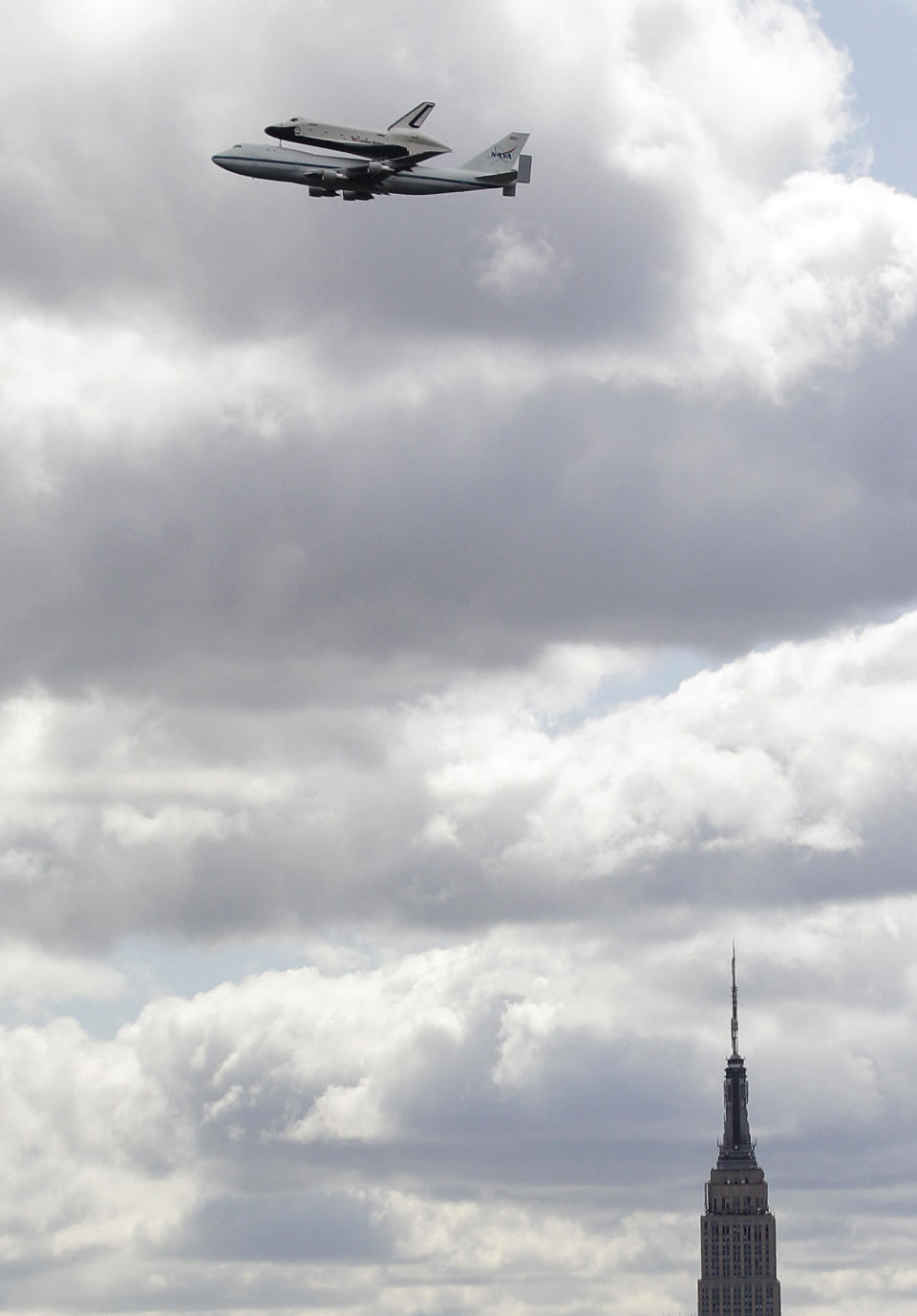 Space shuttle Enterprise, riding on the back of the NASA 747 Shuttle Carrier Aircraft, cruises by the Empire State Building as it makes its way to John F. Kennedy International Airport seen from Union City, N.J., Friday, April 27, 2012. Enterprise is eventually going to make its new home in New York City at the Intrepid Sea, Air and Space Museum. (AP Photo/Julio Cortez)