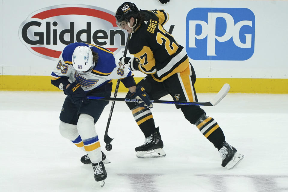 St. Louis Blues' Jake Neighbours (63) fights for thse puck against Pittsburgh Penguins' Ryan Graves (27) during the first period of an NHL hockey game Saturday, Dec. 30, 2023, in Pittsburgh. (AP Photo/Matt Freed)